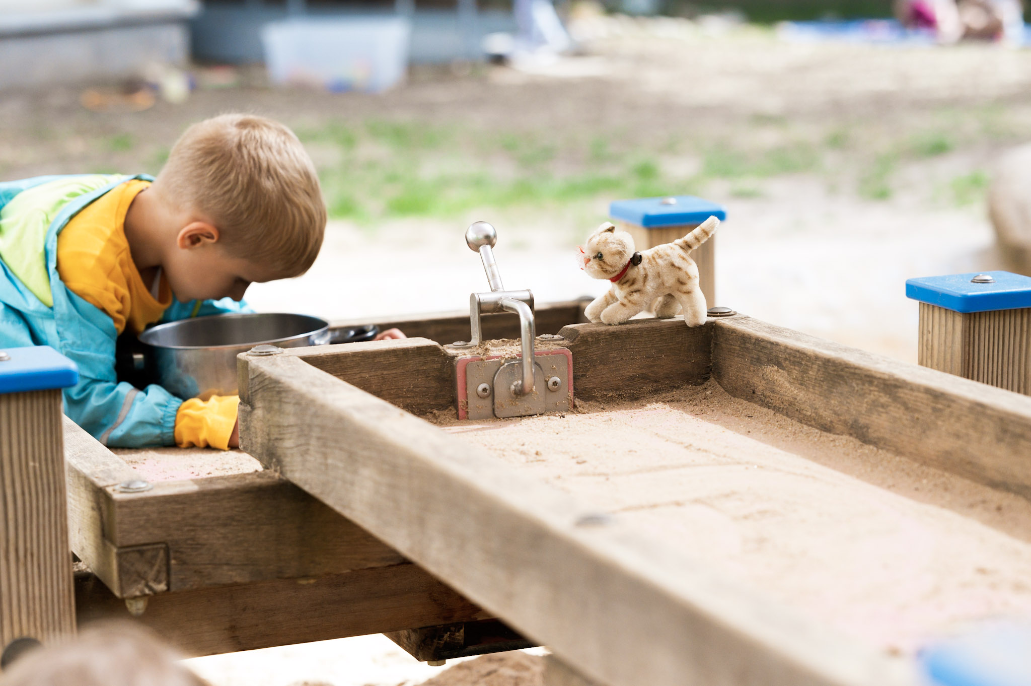 Kind spielt am Sand- und Wasserspieltisch im Garten des Kinderladens